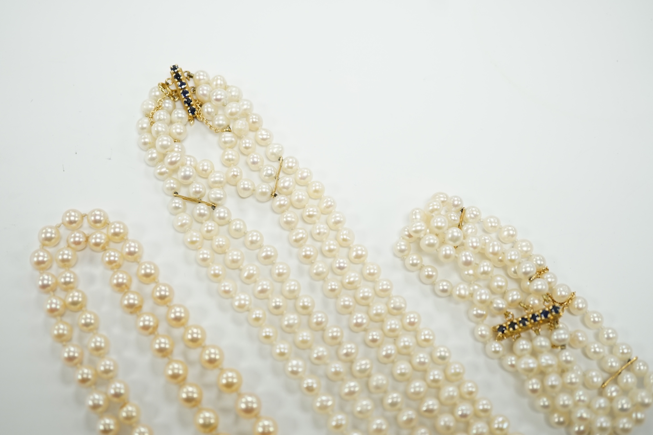 Two Cultured pearl necklaces including a triple strand with yellow metal and sapphire set clasp, 46cm and a matching bracelet.